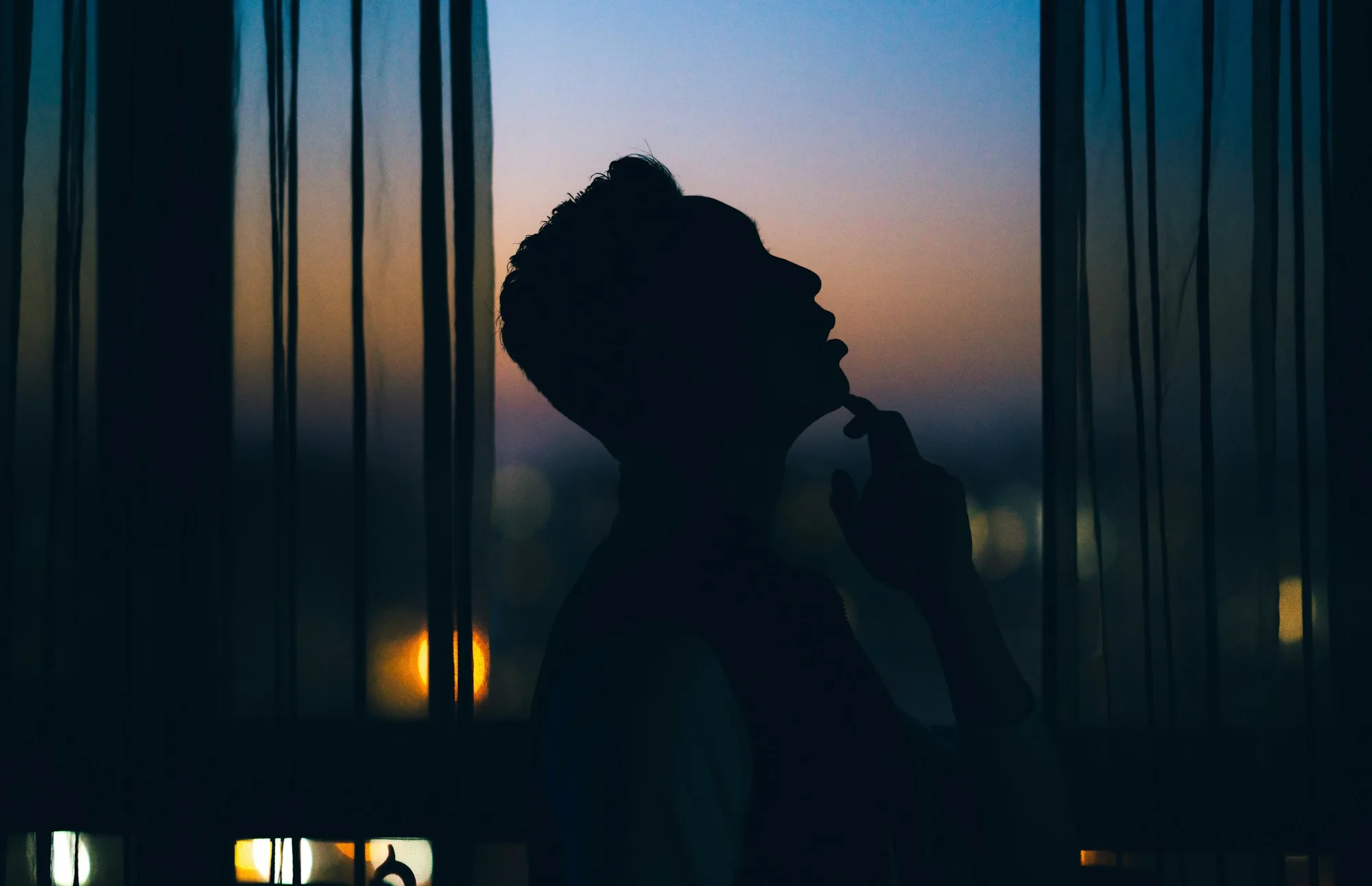 Silhouette standing at a window, contemplative and introspective