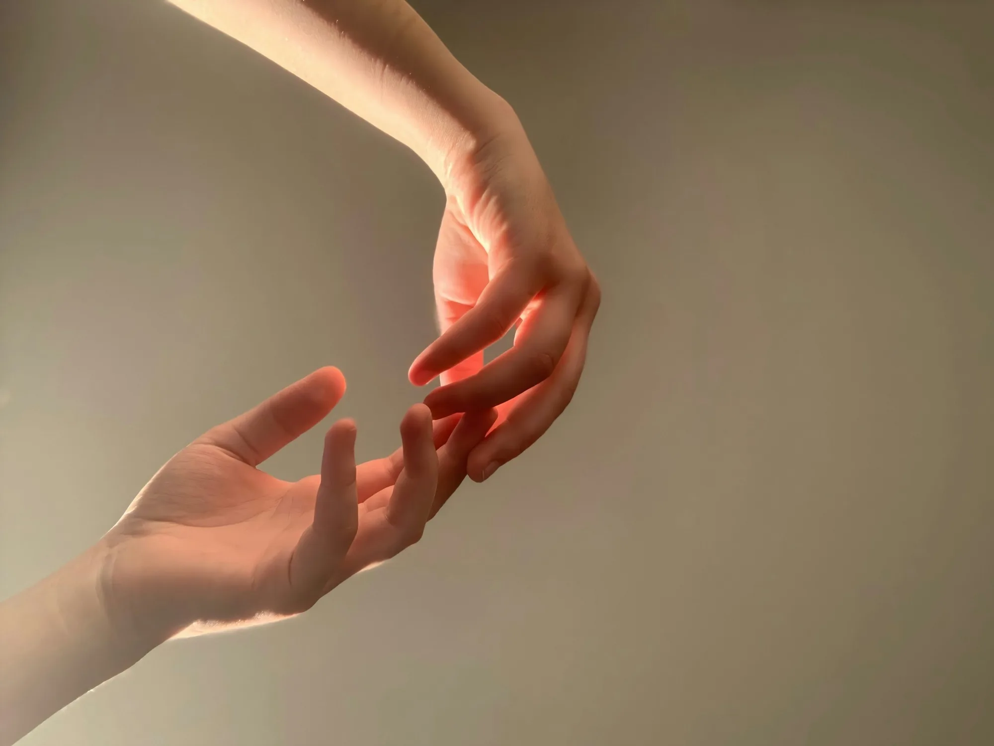 Two hands in gentle contact, warm intimate light